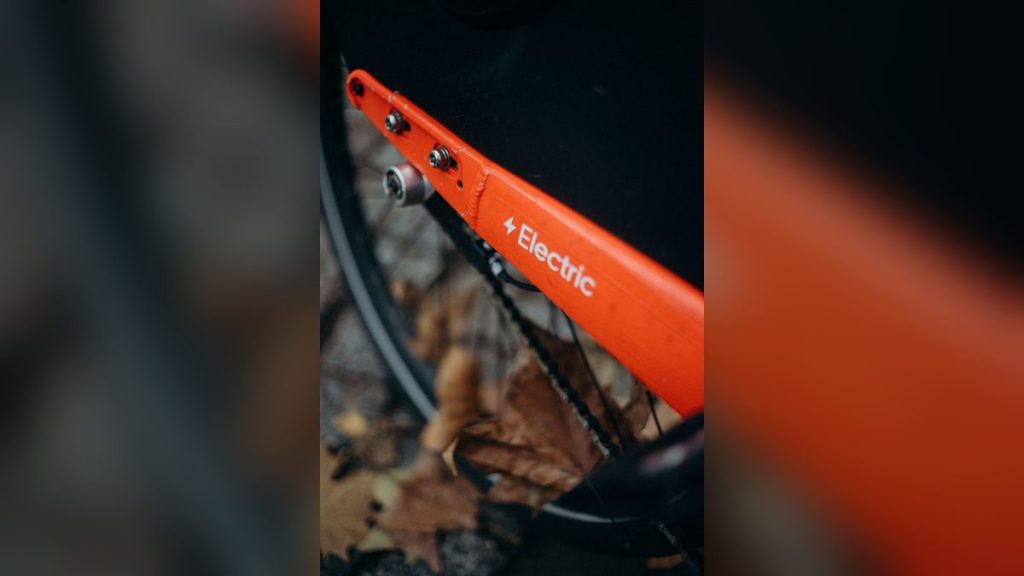 Orange electric bicycle among autumn leaves
