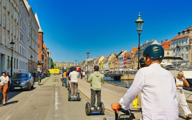 People riding self-balancing scooters on a sunny street