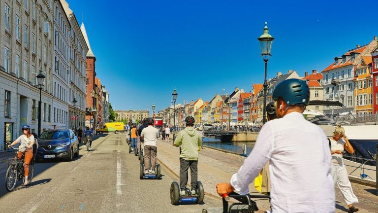 People riding self-balancing scooters on a sunny street
