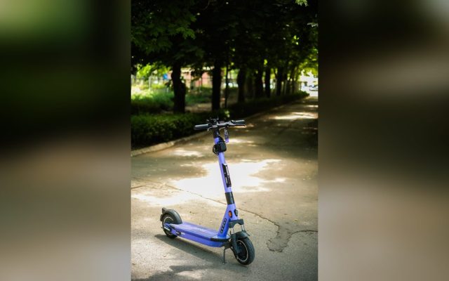 Purple electric scooter on a shaded park path