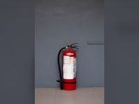 Red fire extinguisher against a grey wall