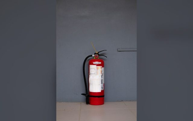 Red fire extinguisher against a grey wall