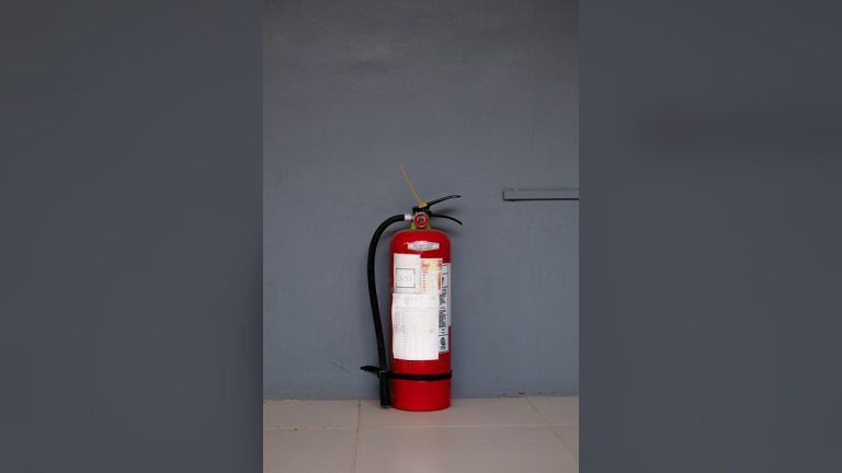 Red fire extinguisher against a grey wall