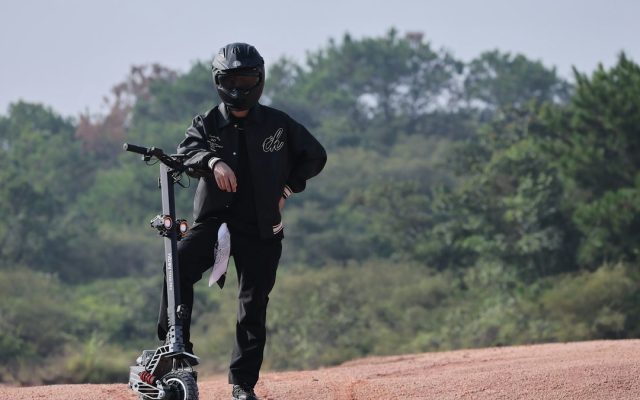 Rider in a helmet with an off-road electric scooter on a dirt trail