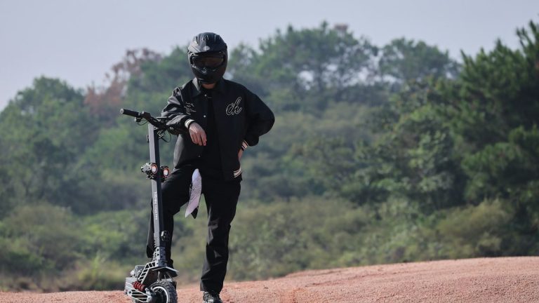 Rider in a helmet with an off-road electric scooter on a dirt trail