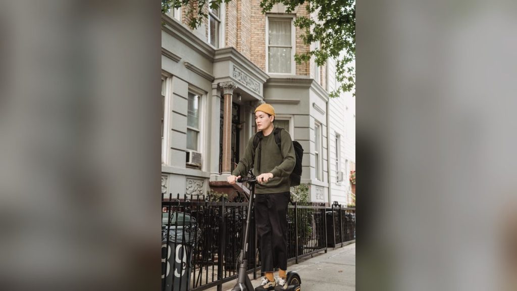 Rider in a yellow sweater on an e-scooter on a quiet street