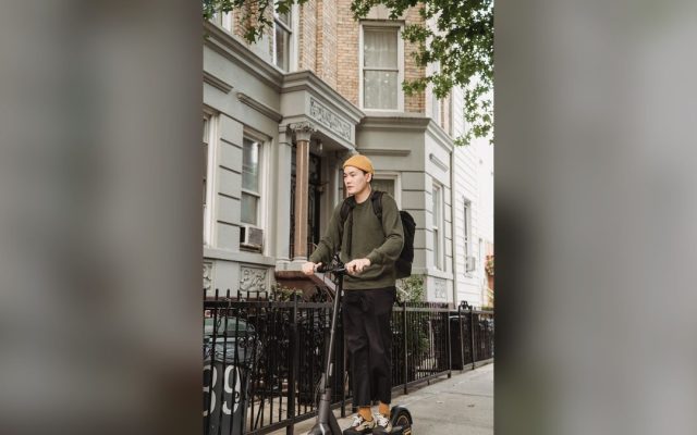 Rider in a yellow sweater on an e-scooter on a quiet street