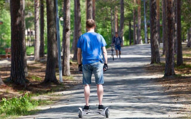 Rider on a self-balancing scooter along a waterfront promenade