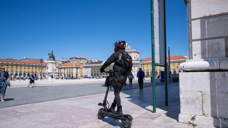 Rider on an electric scooter crossing a sunny city plaza