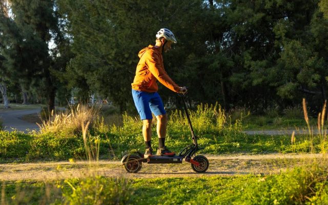 Rider on an off-road electric scooter crossing a grass field