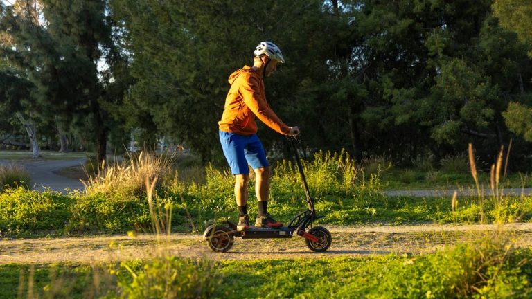 Rider on an off-road electric scooter crossing a grass field