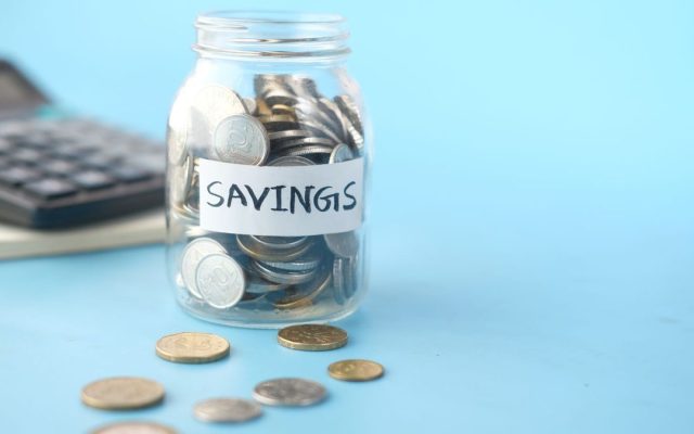 Savings jar filled with coins beside a calculator