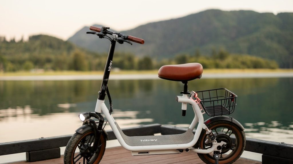 Seated electric scooter with a basket beside a lake