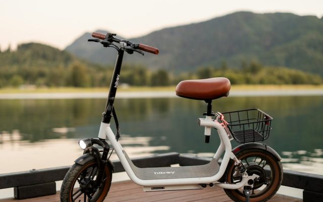 Seated electric scooter with a basket beside a lake
