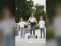 Three children playing with a self-balancing scooter in a park