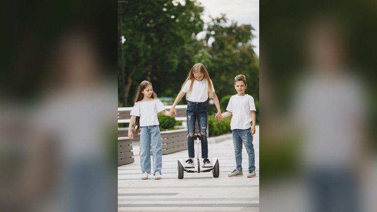 Three children playing with a self-balancing scooter in a park