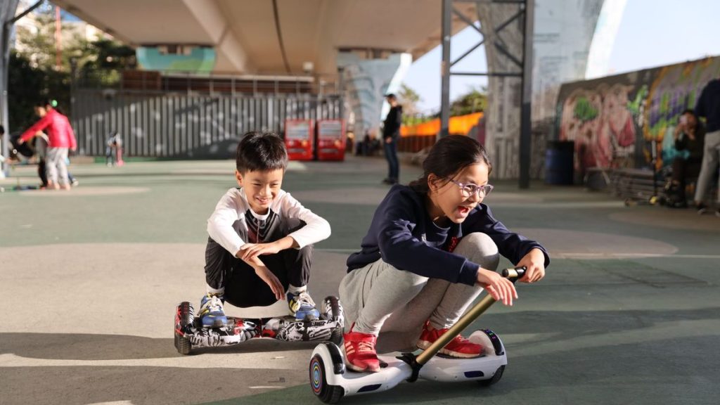 Two children riding hoverboards in a skate park