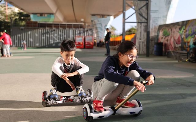Two children riding hoverboards in a skate park