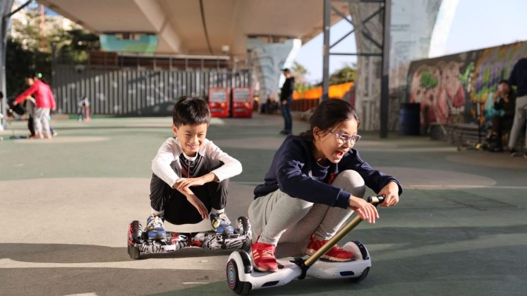 Two children riding hoverboards in a skate park