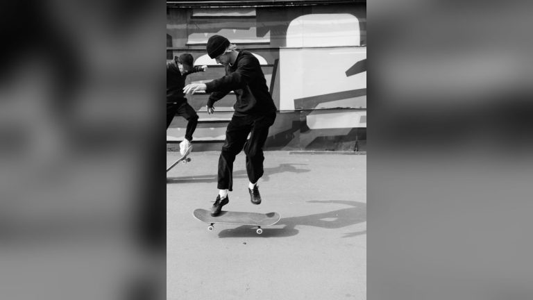 Two skateboarders performing tricks, monochrome