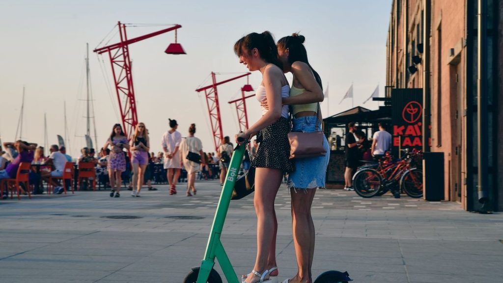 Two young women with an electric scooter at the waterfront