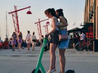 Two young women with an electric scooter at the waterfront