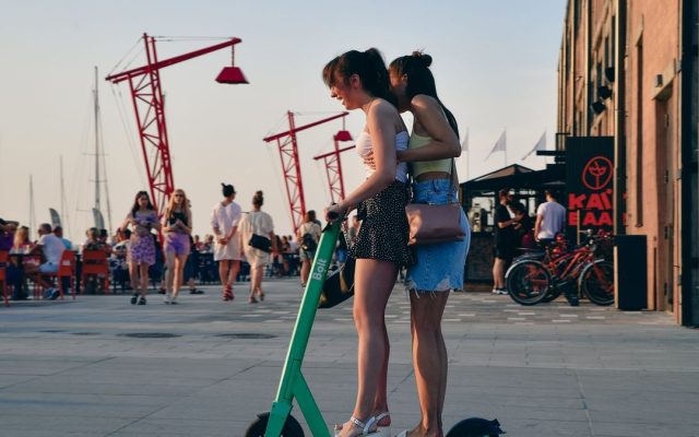 Two young women with an electric scooter at the waterfront