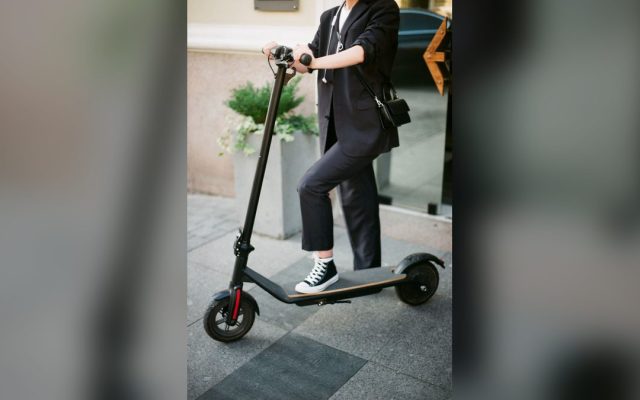 Woman in a suit commuting on an electric scooter