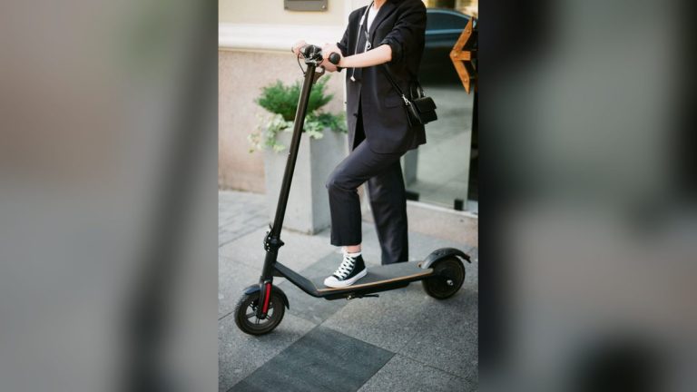 Woman in a suit commuting on an electric scooter
