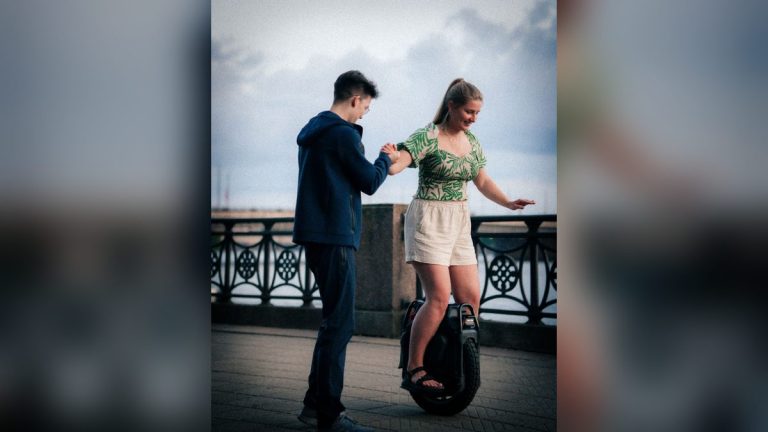 Woman learning to ride an electric unicycle on a riverside path