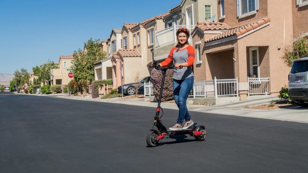 Woman riding a dual-motor electric scooter on a suburban street