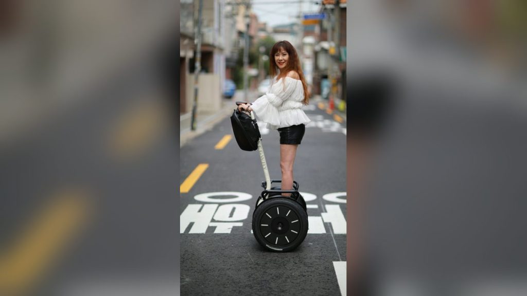 Woman riding a self-balancing scooter along a street