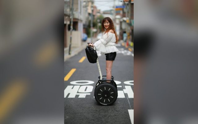 Woman riding a self-balancing scooter along a street