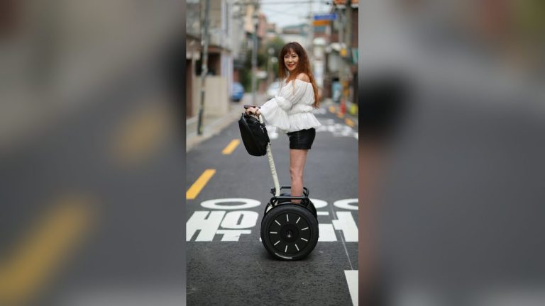 Woman riding a self-balancing scooter along a street