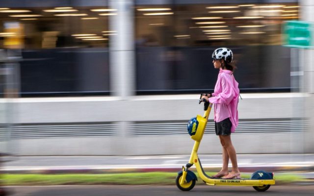 Woman riding a yellow electric scooter with motion blur