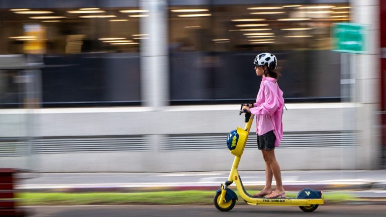 Woman riding a yellow electric scooter with motion blur