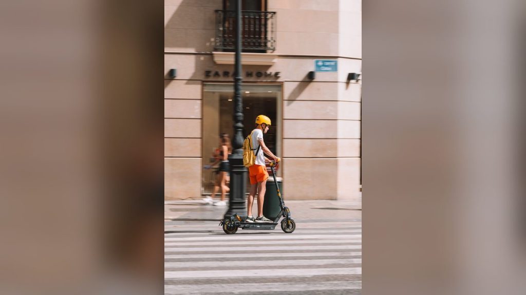 Young man in a helmet riding an electric scooter on a city street