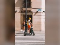 Young man in a helmet riding an electric scooter on a city street