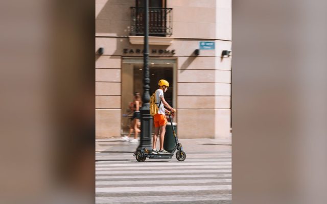 Young man in a helmet riding an electric scooter on a city street