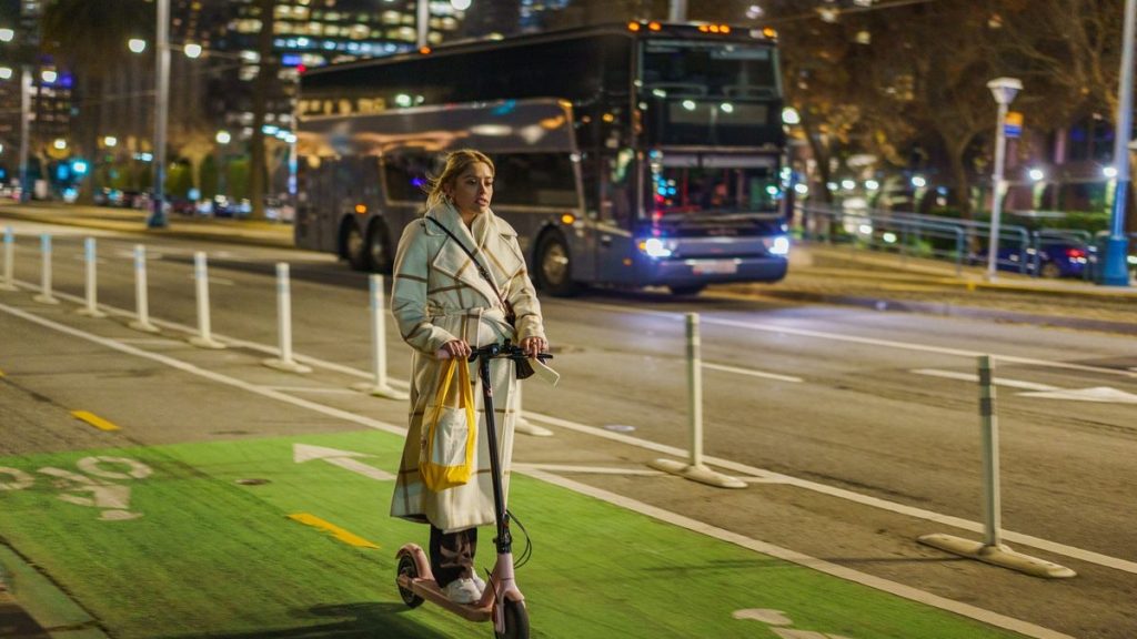 Young woman riding a scooter on a city street at night