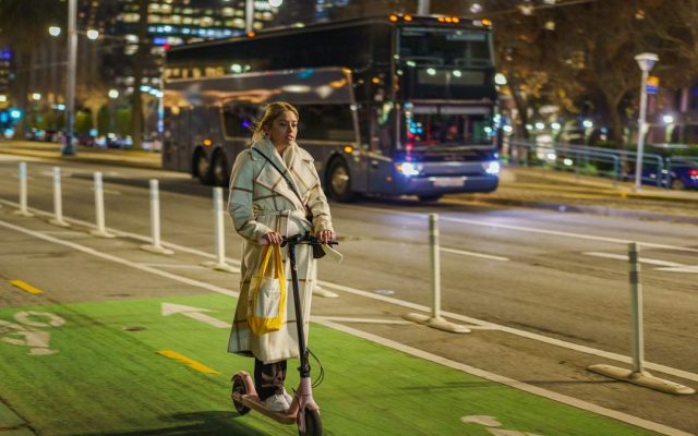 Young woman riding a scooter on a city street at night