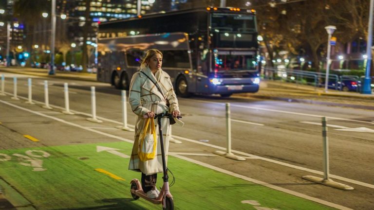 Young woman riding a scooter on a city street at night