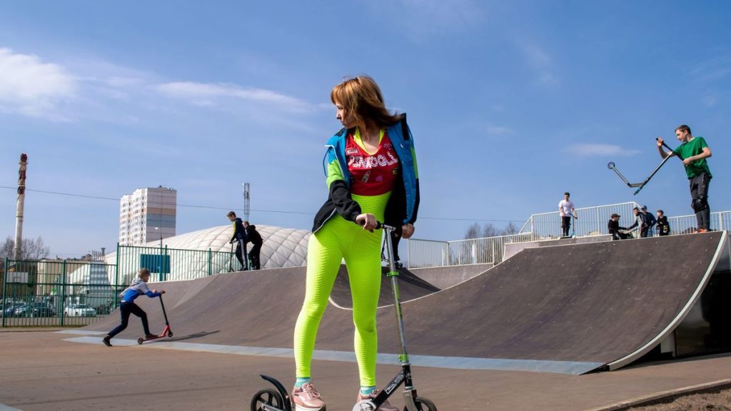 Young woman with a kick scooter in a skate park