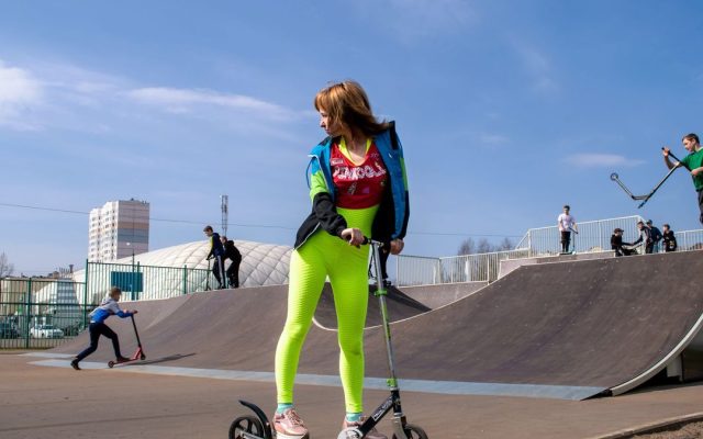 Young woman with a kick scooter in a skate park