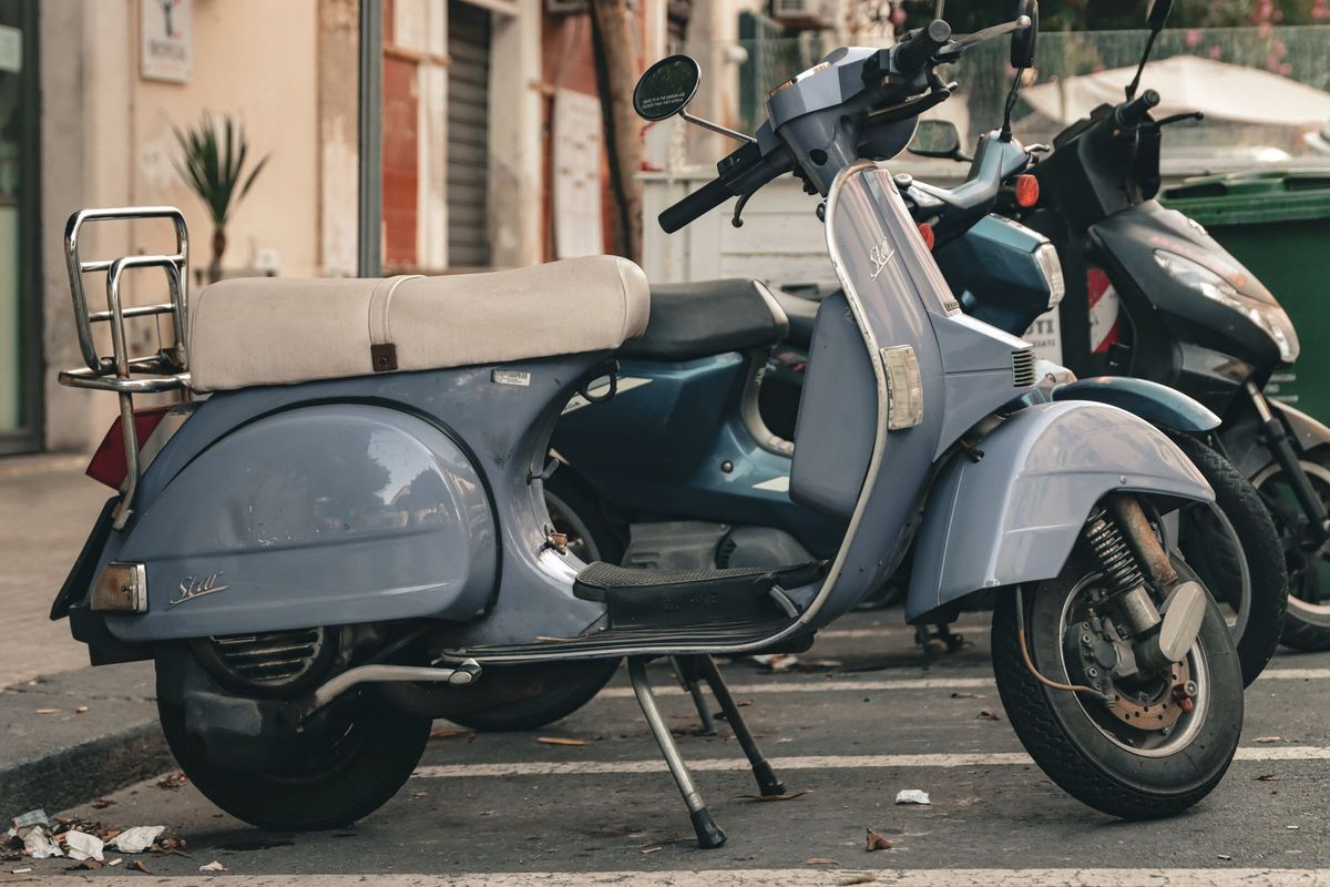 A blue vintage motor scooter parked in Syracuse, Sicily's urban streets