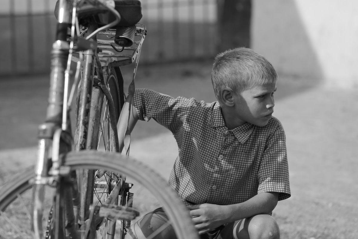 A candid portrait of a young boy repairing his bicycle in Lalakapa, Chhattisgarh
