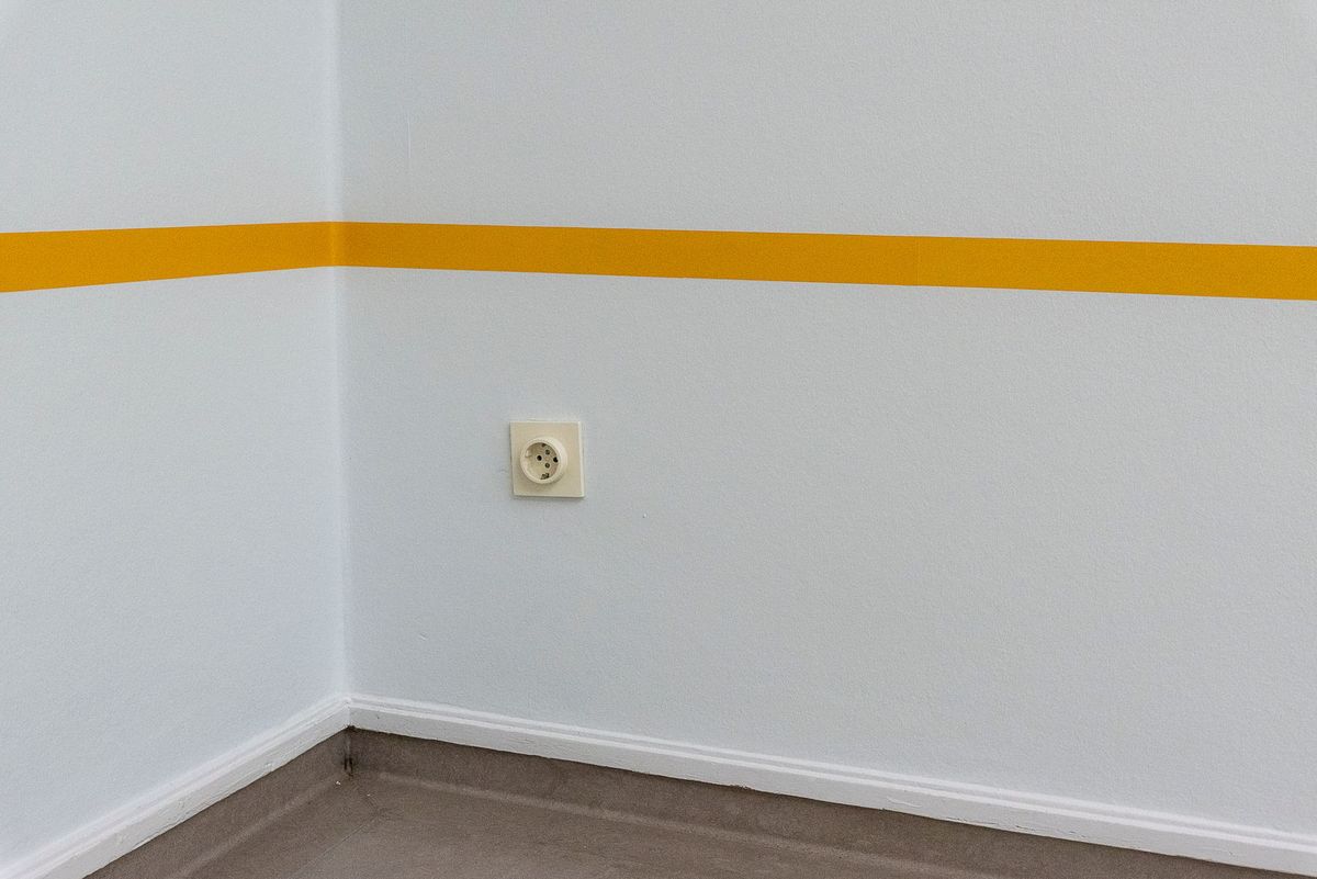 A clean wall with a yellow stripe and an electrical socket adds modern minimalist style