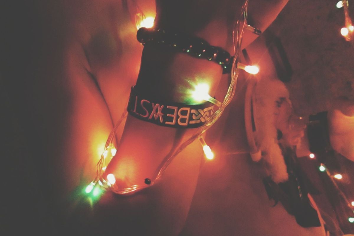 A creative shot of a wrist adorned with bracelets and illuminated by colorful Christmas lights