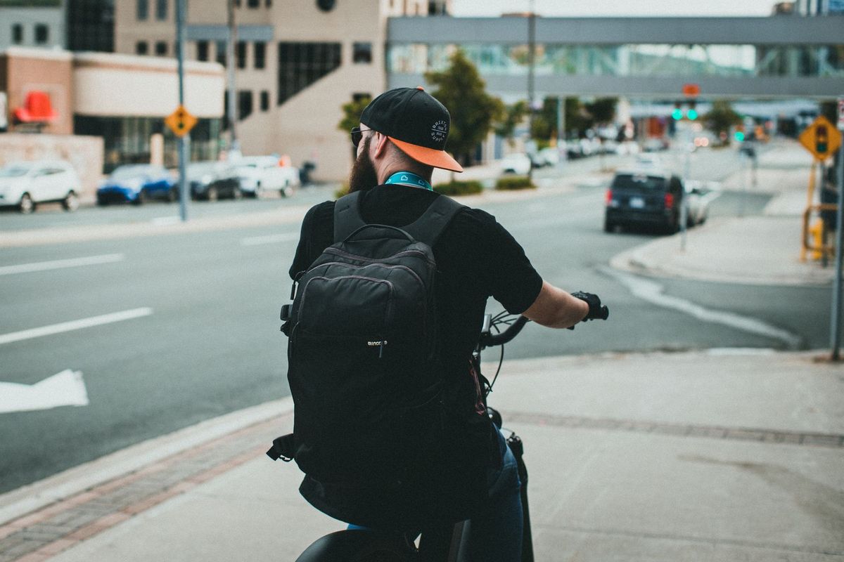 A cyclist with a backpack rides through a city street