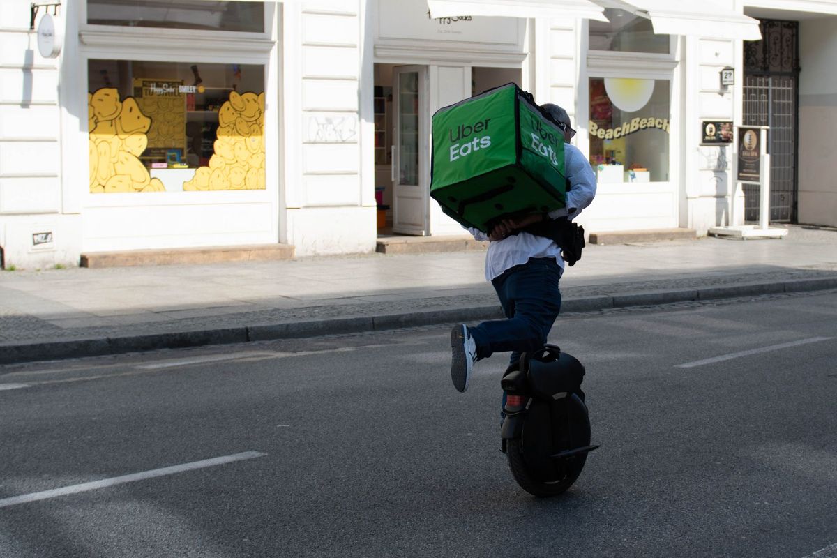 A delivery man rides an electric unicycle with a delivery bag in Warsaw, Poland